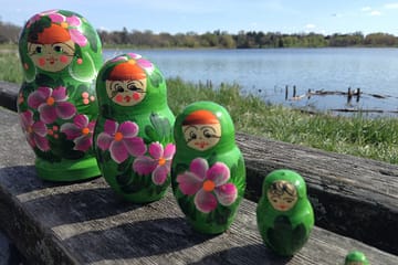 Row of nesting dolls by lake.
