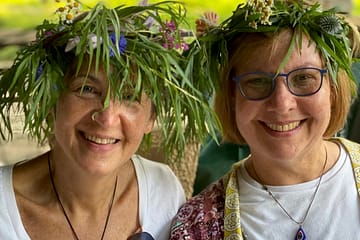Two women smiling with their crowns of willow and flowers
