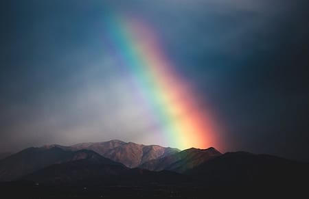 Rainbow over mountain with dark sky