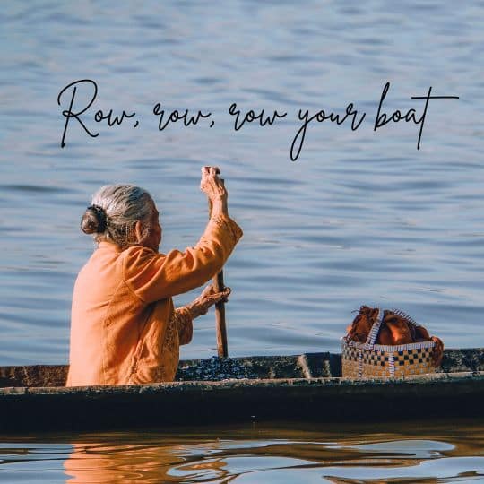 An old south Asian woman paddles her boat.
