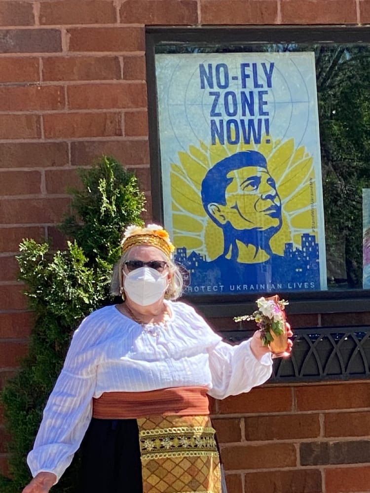 a dancer stands in front of a poster "no fly zone now!"